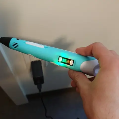 Foto de un comprador con el lápiz 3D encendido, pantalla en verde